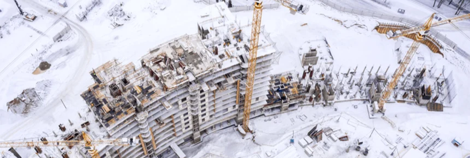 A birds-eye view from above of a multi-story construction project covered in snow.